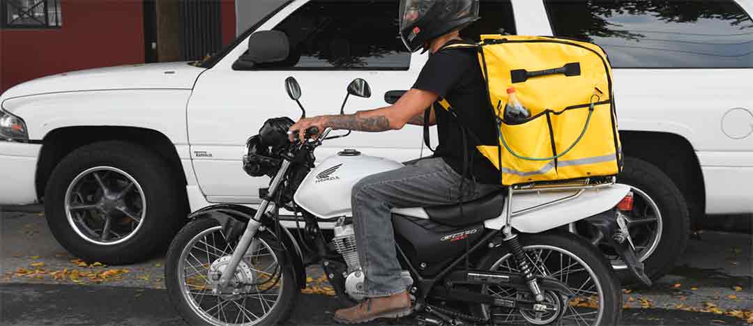 Repartidor en moto con la mochila térmica NAMU amarilla, tipo mochila de DiDi, Uber Eats y Rappi