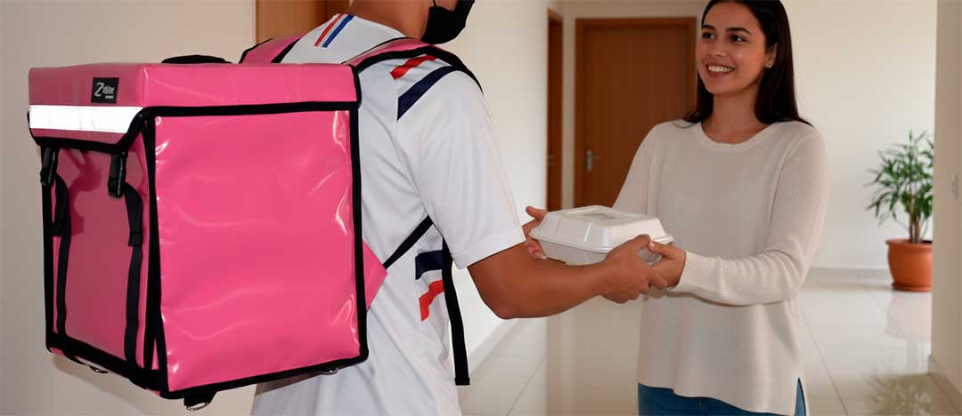 Repartidor con la mochila térmica JUNIOR rosa en la espalda entregando comida